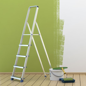 Leiter steht bei Renovierung vor halbfertiger grüner Wand