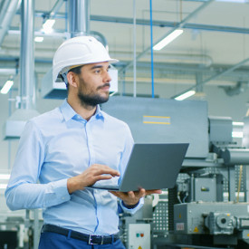 Ingenieur steht mit Laptop in der Produktionshalle