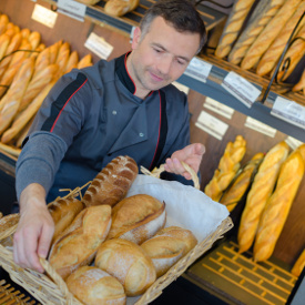 Bäcker sortiert frische Brötchen in seinen Verkaufskorb